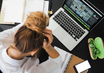 A woman watching her laptop with a phone on the table