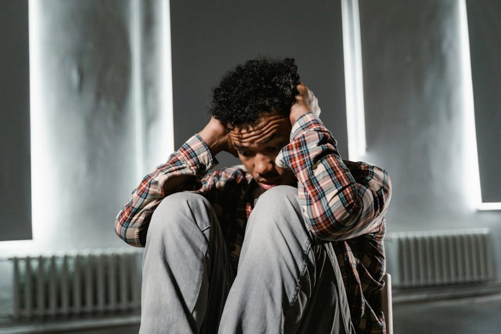 A stressed young man holding his head with his two hands
