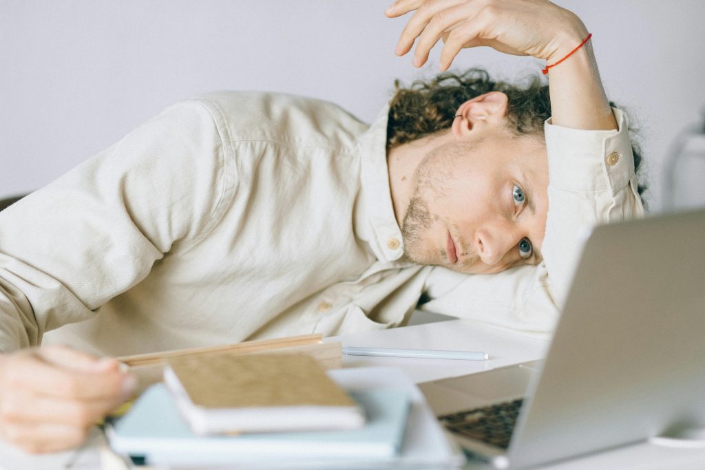 A man resting on a table looking at her PC