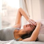 A woman waking up with hands on her head