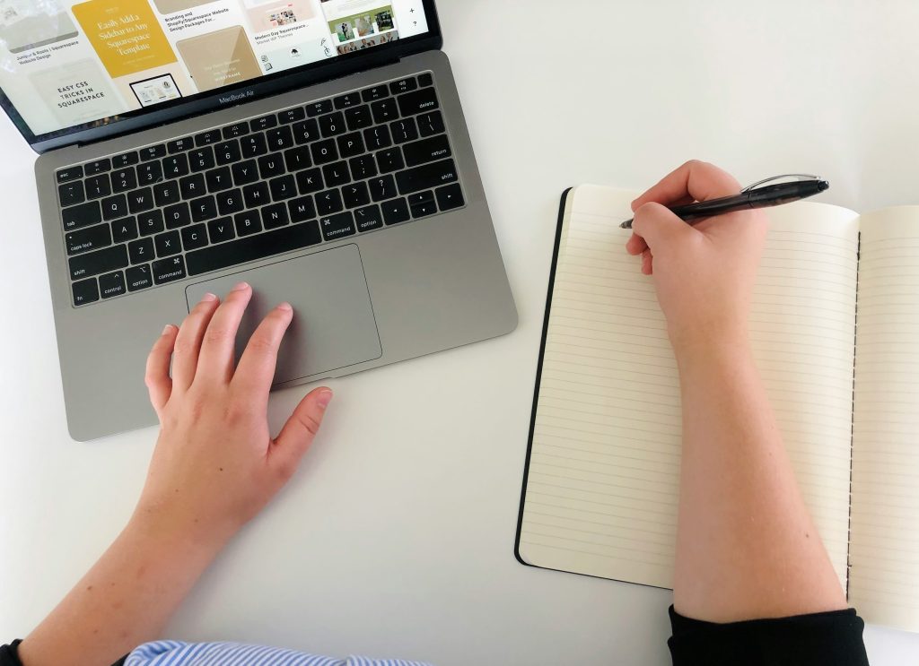 A woman writing with one hand and clicking with the other